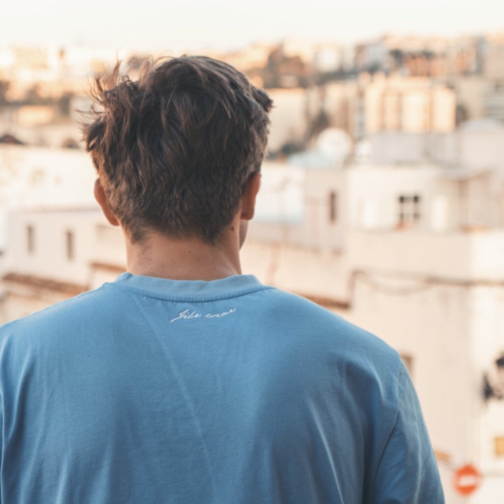 James Blattye in Windsurf apparel in front of blurry old town Tarifa windsurfshop windsurf shop windsurf-shop surfshop windsurfen lernen JibeWear