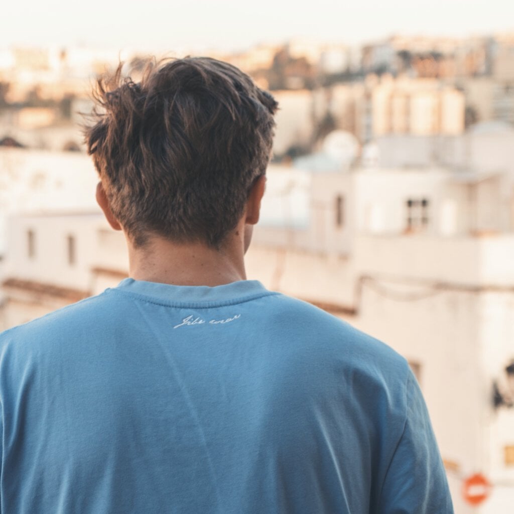 James Blattye in Windsurf apparel in front of blurry old town Tarifa windsurfshop windsurf shop windsurf-shop  surfshop windsurfen lernen JibeWear